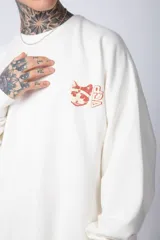 Buzo color crema de corte oversize confeccionado en tela friza con cuello redondo y puños y cintura acanalados. Presenta un pequeño bordado en el frente y un estampado grande en la espalda.