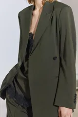 Blazer de Zara Woman Collection color verde musgo, de corte recto, con cuello solapa y manga larga. Tiene bolsillos de vivo en el delantero y cierre frontal cruzado con un botón.