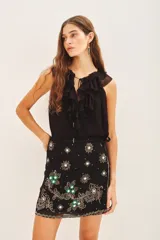 Minifalda negra con short interno, de corte cruzado con lazo lateral y bordados florales en frente y espalda.