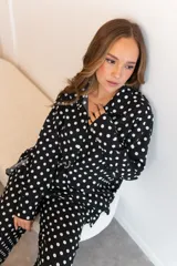 Camisa negra con estampado de lunares blancos, de manga larga y cuello clásico.