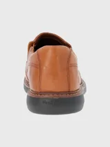 Zapato de vestir color marrón, sin cordones, de cuero vacuno liso. Tiene elásticos laterales, plantilla de cuero y algodón orgánico, y suela de goma EVA.