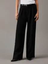 Pantalón negro de crepé elástico, corte recto, cintura plisada, bragueta con cremallera y bolsillos con ranura.