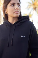 Canguro negro con capucha y cordones ajustables, bolsillo tipo canguro y logo pequeño en el pecho.