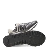 Championes New Balance modelo 574 Classics Traditionnels, color gris oscuro metalizado con detalles en beige claro. Presentan el logo 'N' en negro con borde beige y cordones color crema. La entresuela es beige con motas oscuras.