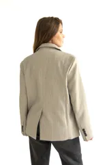 Blazer gris de silueta recta y textura sutil, con solapas de muesca, cierre con dos botones, bolsillos con solapa y puños con cuatro botones.