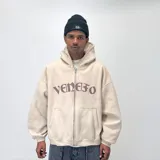 Canguro beige con capucha y cierre frontal, de corte holgado y con texto gótico en el pecho.