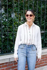 Camisa blanca de algodón con bordados de flores rosas en cuello, frente y puños, corte clásico y cierre con botones.