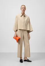Pantalón tobillero color beige, de corte recto, con trabillas, bolsillos laterales y bolsillos de vivo en la espalda.