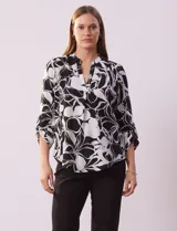 Blusa de gasa estampada en blanco y negro, marca Floral & Ivy. Tiene cuello a la base con escote en V y mangas 3/4 regulables con presilla y botón.