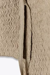 Top mostaza de cuello barco y manga larga con textura. Tiene lazadas ajustables en el bajo.