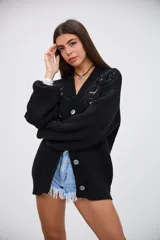 Saco de punto grueso color negro, con escote en V, cierre frontal de botones y mangas largas. Presenta detalles de bordado con lentejuelas y canutillos negros y plateados en la parte superior delantera.