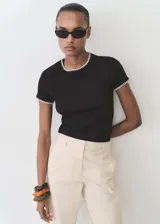 Camiseta negra de manga corta con cuello redondo y ribetes blancos en cuello y mangas.