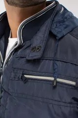 Chaqueta de nylon de color azul marino, con bolsillos con cierre y capucha desmontable.