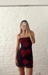 Vestido corto negro con estampado de flores rojas, breteles finos y ruedo con volados.
