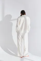 Conjunto de pijama blanco de lino y viscosa, compuesto por un corpiño de encaje, una camisa de mangas largas y un pantalón capri con lazo en la cintura.