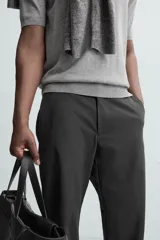 Pantalón chino de vestir negro, corte slim fit, con bolsillos laterales y traseros. Cierre frontal con cremallera y botón.