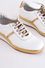 Zapatillas deportivas acordonadas color beige con suela de plataforma blanca y detalles en color plata.