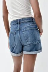 Bermuda de jean celeste, tiro alto, corte mom fit, con trabillas y cinco bolsillos.