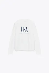 Sudadera blanca de algodón con cuello redondo, manga larga y texto bordado en azul marino en el frente que dice 'USA' y 'Tennis Club Division'.