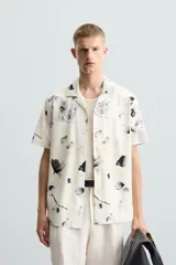 Camisa de manga corta con cuello bowling y estampado floral en tonos blanco y negro.