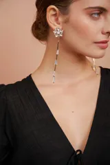 Aros largos dorados con base de flor de cinco pétalos y colgantes de cadena fina con cuentas de cristal.
