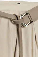 Falda midi color beige con textura rústica, tiro alto, pinzas delanteras, corte evasé y cinturón ancho con hebilla metálica.