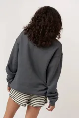 Sweater gris oscuro, de textura afelpada o tipo borreguito, con cuello redondo y puños y ruedo acanalados. Estampado frontal con texto en mayúsculas "WILD NIGHTS" y un dibujo de una copa de cóctel.