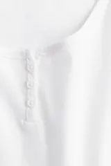 Remera blanca de algodón con escote en U y tapeta de botones.