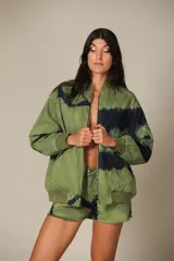 Campera bomber verde con estampado tie-dye en azul marino, cierre frontal y puños y cintura elastizados.