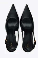 Zapato de tacón negro con efecto relieve en el cuerpo, tira trasera con hebilla ajustable, tacón fino y acabado en punta.
