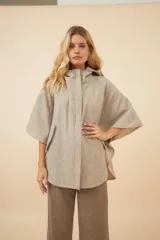 Capa amplia color marrón con capucha, cierre metálico y bolsillos delanteros. Espalda con canesú y botones laterales para generar la manga.