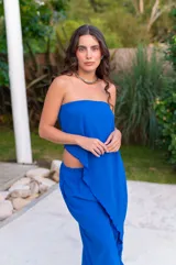 Conjunto de dos piezas color beige claro, compuesto por un top strapless con bajo asimétrico y un pantalón ancho de tiro alto.