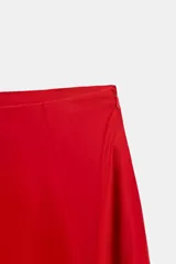 Falda midi roja de tiro medio con pliegues y cierre lateral con cremallera oculta.
