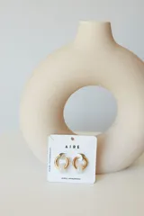 Aros de acero quirúrgico hipoalergénico con piedras naturales azules. Diseño de aro con dije circular colgante.