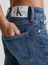 Jeans de denim elástico azul con efecto lavado, corte skinny, tiro bajo, cinco bolsillos y cierre con cremallera.