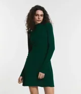 Vestido de punto blanco, manga larga, con cuello alto y corte evasé.