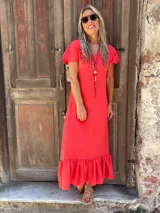 Vestido midi de seda color rojo, con escote en V, mangas cortas con volados y un amplio volado en el ruedo.