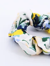 Colero de tela con estampado floral en tonos azul, amarillo, verde y beige sobre fondo blanco.