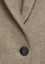 Blazer marrón con estampado de micro pata de gallo, cuello de solapa, cierre frontal con botón y bolsillos delanteros con solapa.