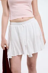 Minifalda blanca de viscosa con cintura elastizada y cordón ajustable con borlas.