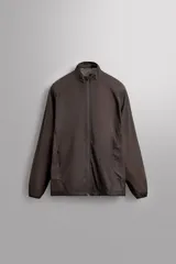 Cazadora relaxed fit confeccionada en tejido técnico ligero color marrón. Cuello subido, manga larga acabada en puño con elástico, bolsillos frontales en cadera con cierre de cremallera oculta en costura y cierre frontal con cremallera.