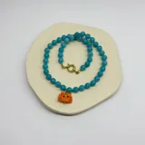 Collar de cuentas de ágata turquesa de 8mm con separadores de hilo turquesa y dije de cangrejo de cristal de Murano. Cierre de acero con baño de oro.