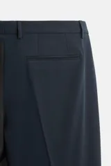 Pantalón de vestir azul marino, de corte slim fit, con bolsillos laterales y traseros de vivo con botón. Se ajusta a la cintura con cierre frontal con cremallera y botón.