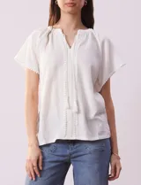 Blusa blanca texturada, marca Sabrina Lauren, con cuello a la base, escote en V con puntilla y lazo, mangas cortas amplias y aplique de puntilla.