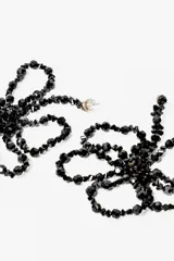 Par de aros colgantes con forma de flor, hechos de cuentas negras.