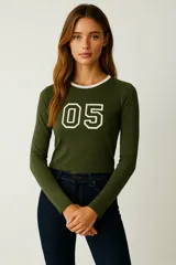 Remera de manga larga color verde militar, ajustada al cuerpo, con cuello redondo ribeteado en blanco y estampado frontal con el número 05 en blanco con borde negro.