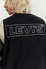 Campera estilo varsity con cuerpo de lana azul marino y mangas de cuero sintético en color negro. Presenta cuello, puños y ruedo acanalados con rayas blancas, cierre frontal con botones a presión y bolsillos laterales.