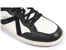 Zapatillas urbanas Schutz modelo Ben, color blanco y negro con detalles de glitter. Presentan cordones negros, logo de la marca en dorado y suela de goma.