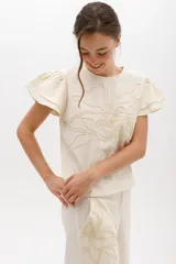 Blusa celeste de lino con bordado en relieve de formas orgánicas y terminaciones desflecadas.