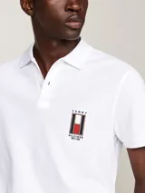 Chomba blanca de piqué de algodón con cuello clásico, cartera de dos botones y logo vertical de Tommy Hilfiger bordado en el pecho. Corte regular.